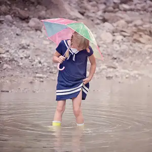 Girl holding an umbrella and wading through a puddle.
