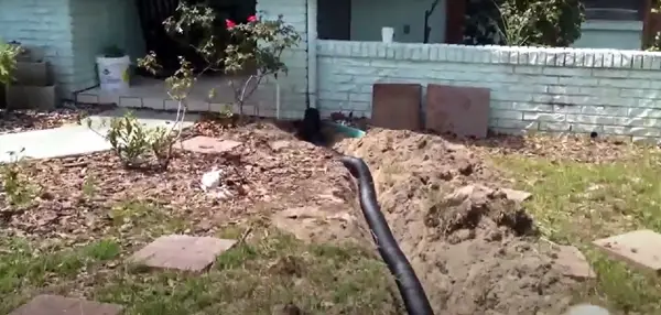 Drain tile being installed to remove water from a roof downspout.