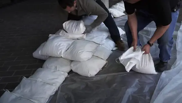 White sand bags being put in front of a house doorway to prevent flood waters from entering the house. Image: LA County Public Works