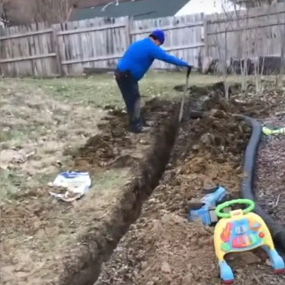 A man digging a French drain trench.